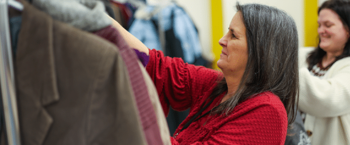 a woman looking at a rack of coats